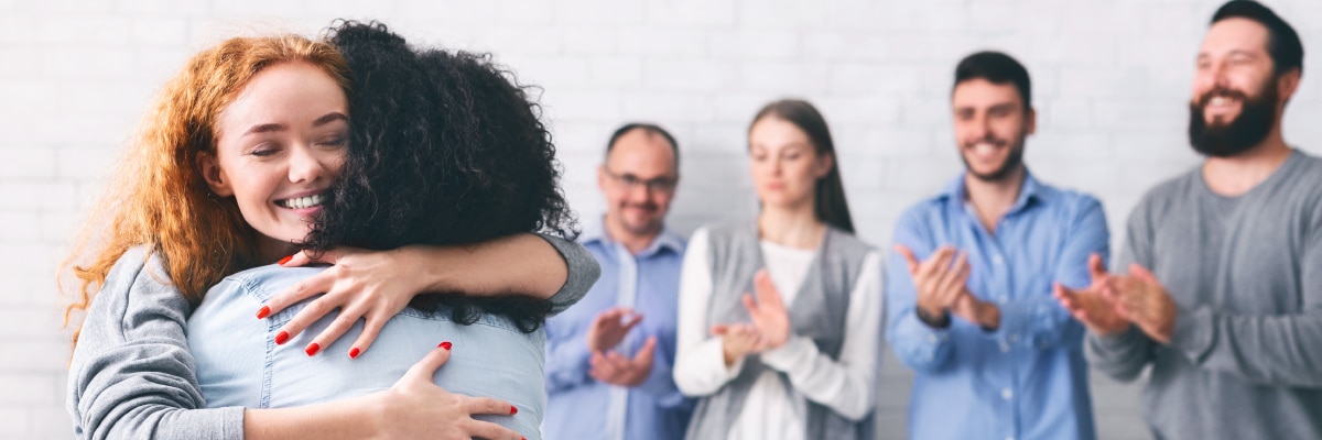 Happy people embracing each other after successful group meeting in rehab | Brazos Place